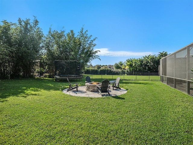 view of yard with a patio area, a fire pit, a trampoline, and fence