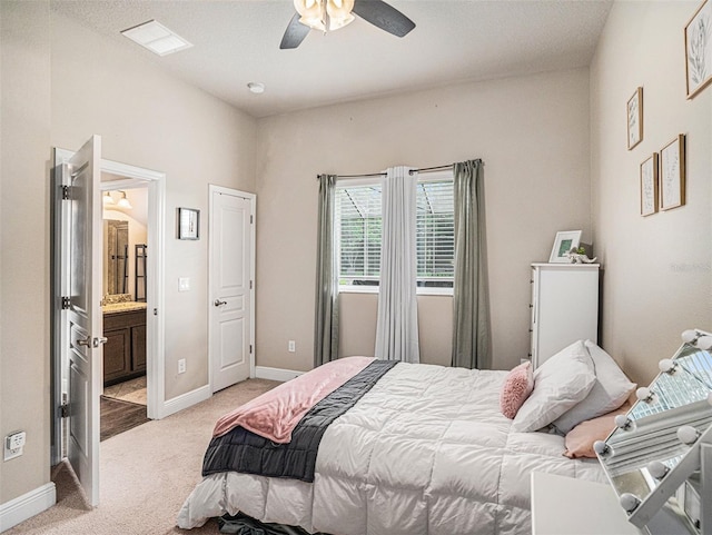 bedroom featuring visible vents, baseboards, light colored carpet, ensuite bath, and a ceiling fan