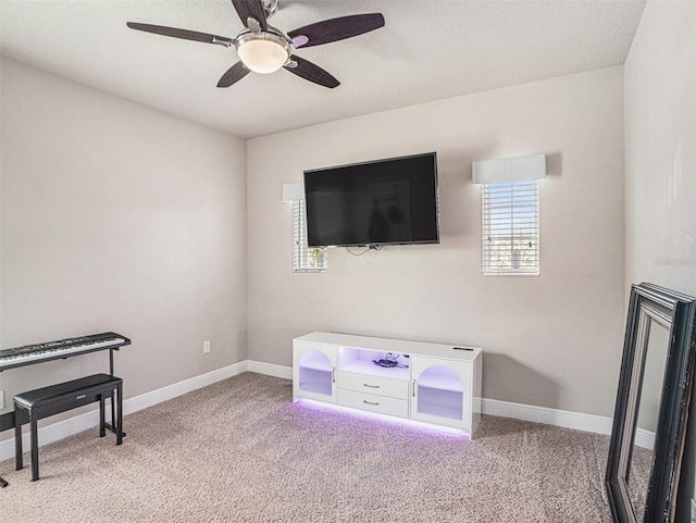 interior space with a textured ceiling, baseboards, carpet, and ceiling fan