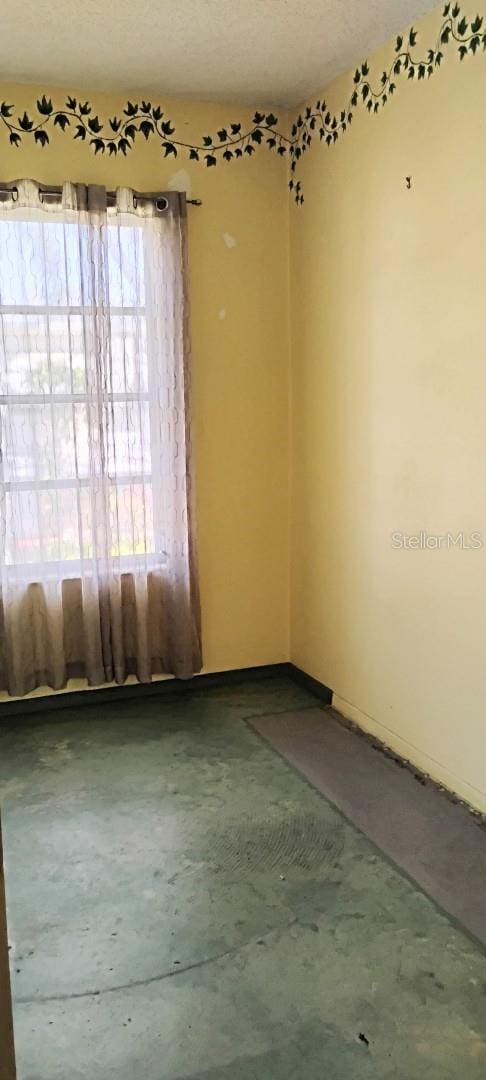 unfurnished room featuring a textured ceiling and concrete flooring