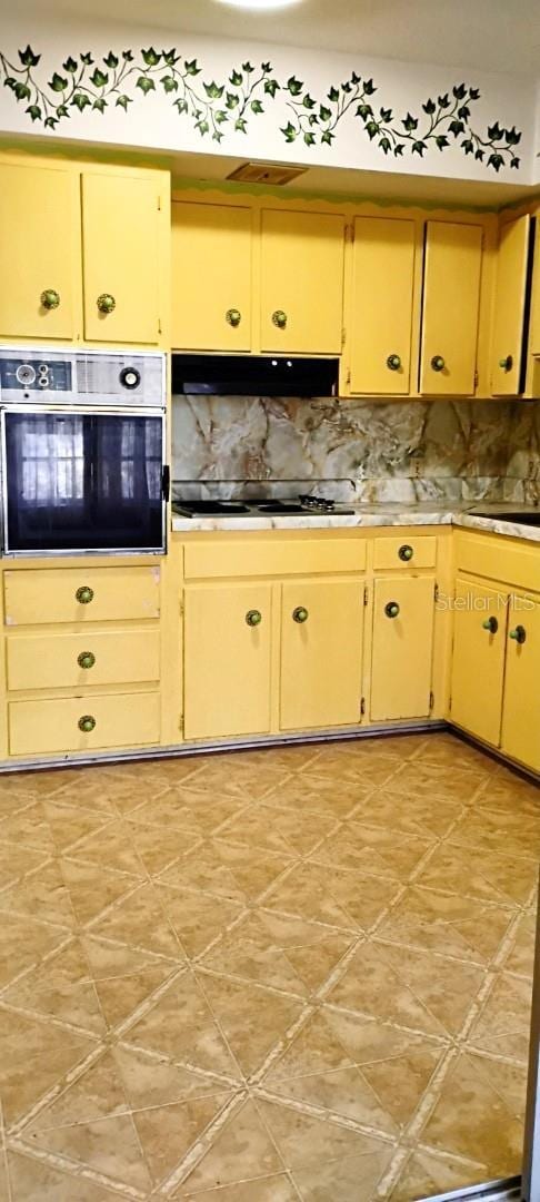 kitchen featuring under cabinet range hood, stovetop, tasteful backsplash, and wall oven