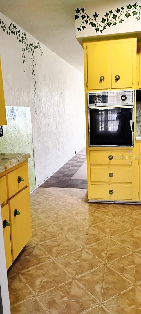 kitchen with stainless steel oven and yellow cabinets