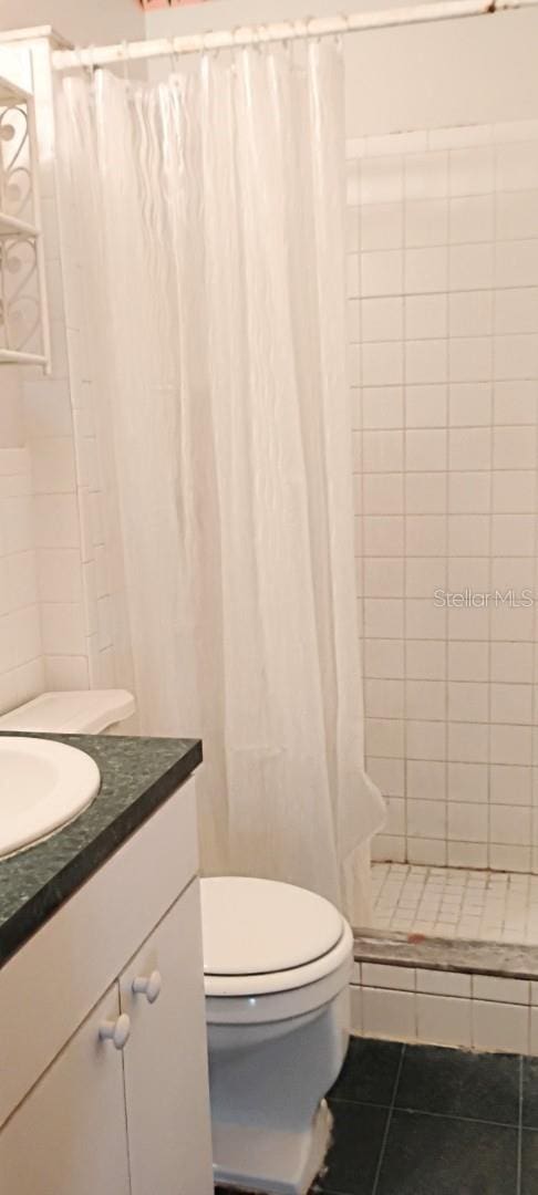 full bathroom with tile patterned floors, toilet, a shower stall, and vanity