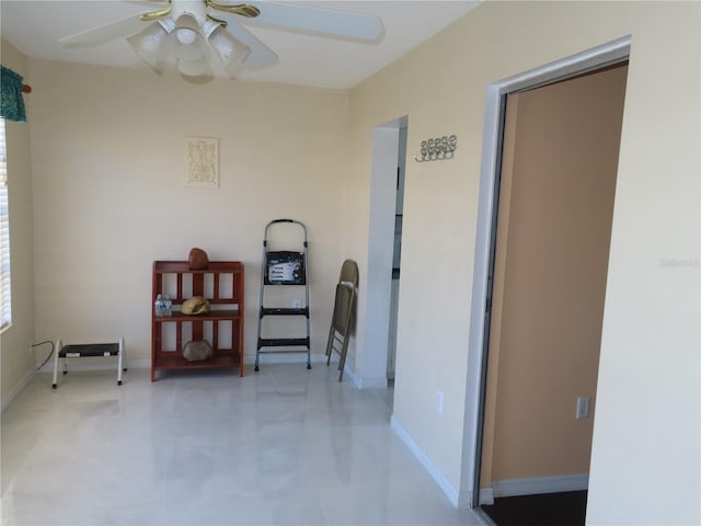 sitting room featuring a ceiling fan and baseboards