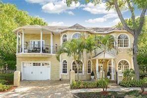 view of front of home with a balcony, an attached garage, driveway, and fence