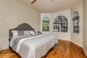 bedroom featuring baseboards, wood finished floors, and a ceiling fan