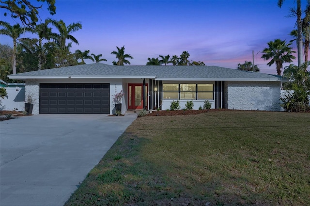 view of front facade with a front yard, a shingled roof, stucco siding, concrete driveway, and a garage