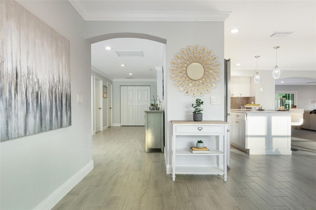 hall with baseboards, recessed lighting, arched walkways, ornamental molding, and light wood-style floors