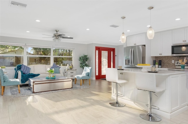 kitchen with visible vents, a breakfast bar, tasteful backsplash, appliances with stainless steel finishes, and light countertops