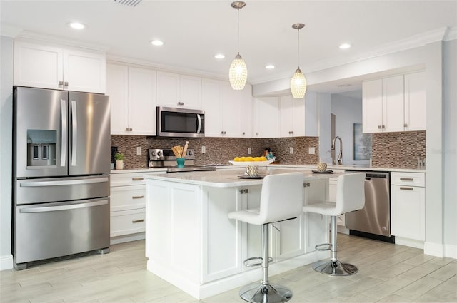 kitchen with stainless steel appliances, white cabinets, ornamental molding, and light countertops