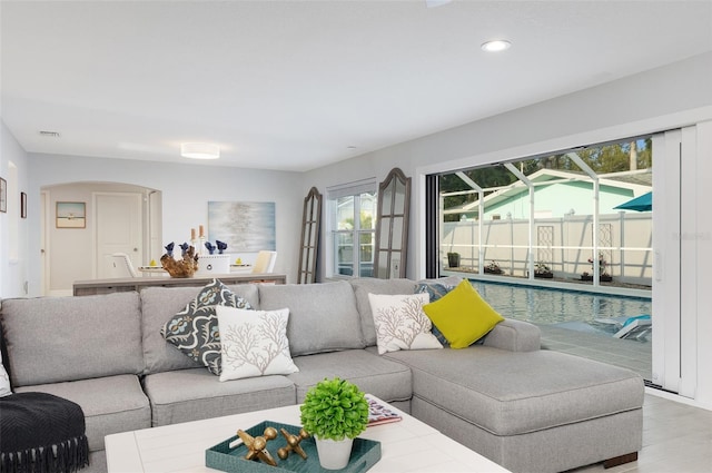 living room featuring wood finished floors, recessed lighting, visible vents, and arched walkways