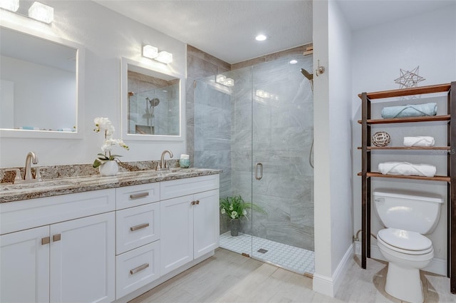 full bathroom with double vanity, a shower stall, toilet, and a sink