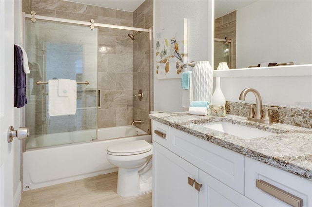 bathroom with vanity, toilet, and combined bath / shower with glass door