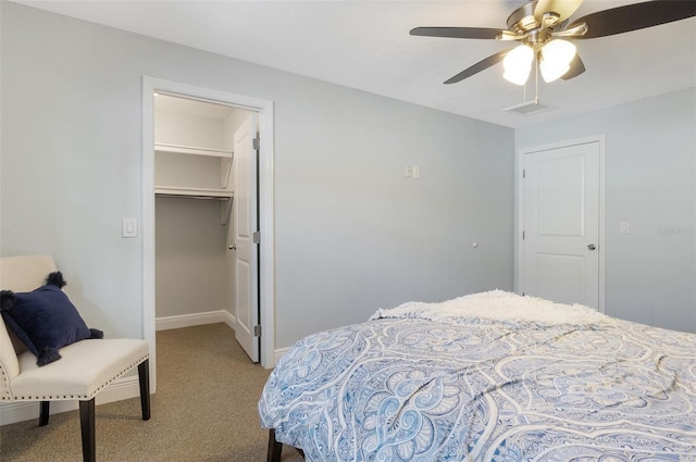 bedroom featuring a spacious closet, baseboards, ceiling fan, carpet, and a closet