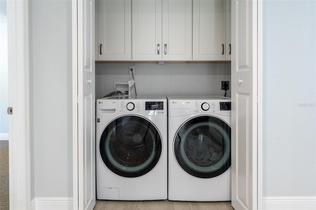 clothes washing area with cabinet space and independent washer and dryer