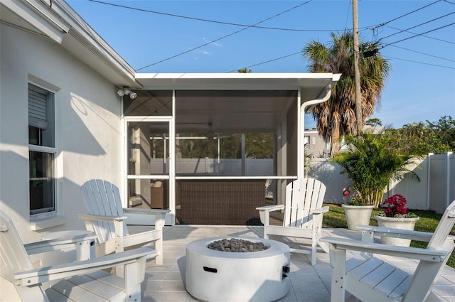 view of patio / terrace with a fire pit, fence, and a sunroom