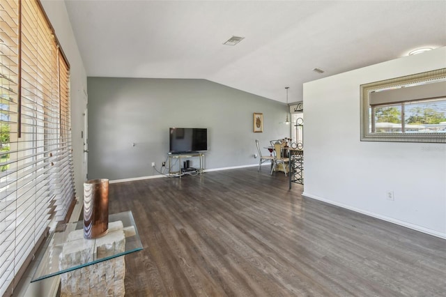 unfurnished living room featuring lofted ceiling, wood finished floors, visible vents, and baseboards