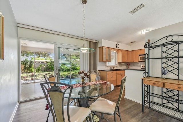 dining space featuring visible vents, plenty of natural light, lofted ceiling, and dark wood-style floors