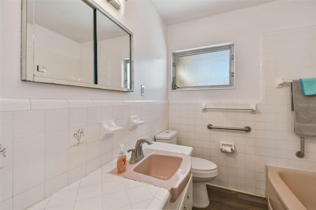 full bath with a wainscoted wall, toilet, a tub, and a sink