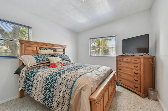 bedroom with vaulted ceiling, baseboards, and a textured ceiling