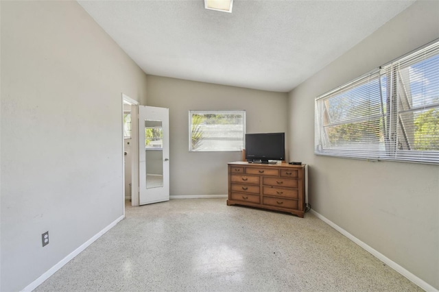 unfurnished bedroom with baseboards, multiple windows, and a textured ceiling