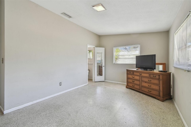 unfurnished bedroom featuring visible vents, a textured ceiling, and baseboards