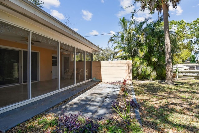 view of yard with a patio, fence, a sunroom, and ceiling fan