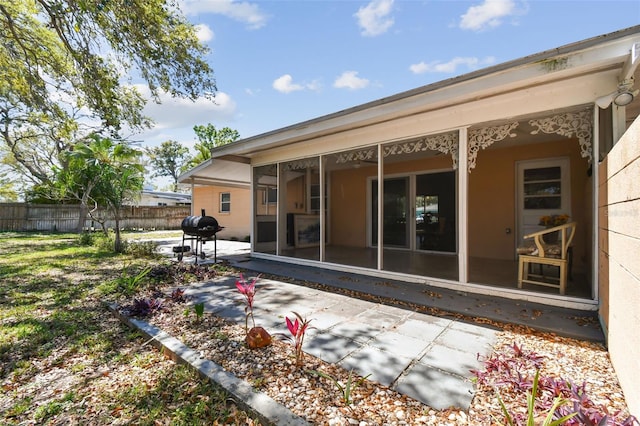 rear view of house with a patio area, fence, and a sunroom