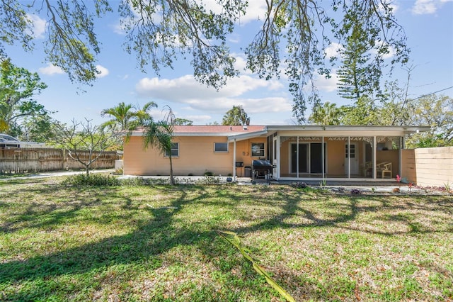 rear view of house featuring fence private yard, a yard, and a sunroom