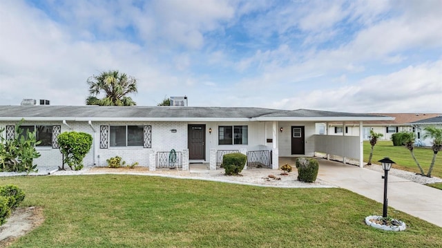 ranch-style home with a carport, a front yard, brick siding, and driveway