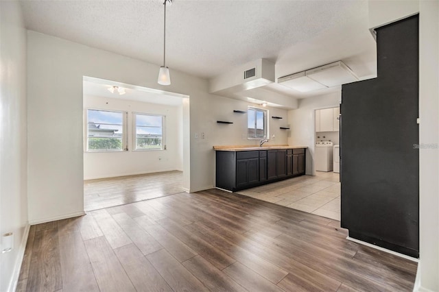 kitchen with visible vents, light wood-style floors, washing machine and dryer, and a textured ceiling