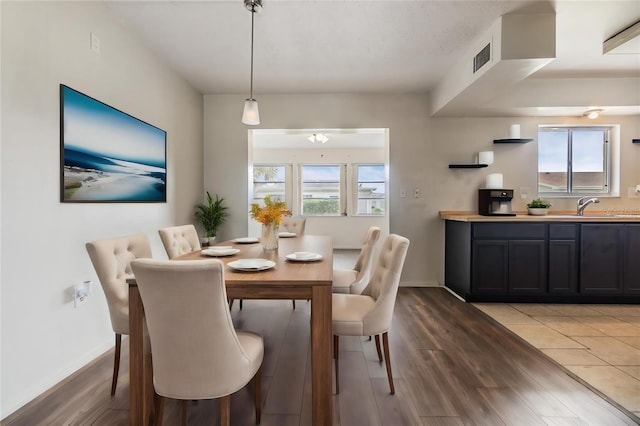 dining room featuring light wood finished floors, visible vents, and baseboards