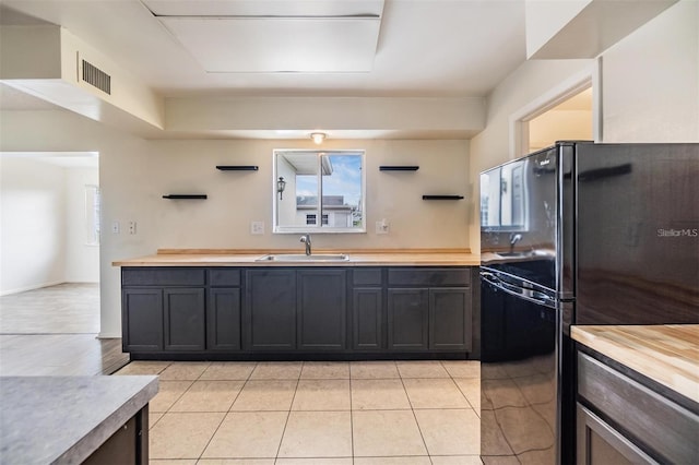 kitchen featuring visible vents, a sink, freestanding refrigerator, wood counters, and open shelves