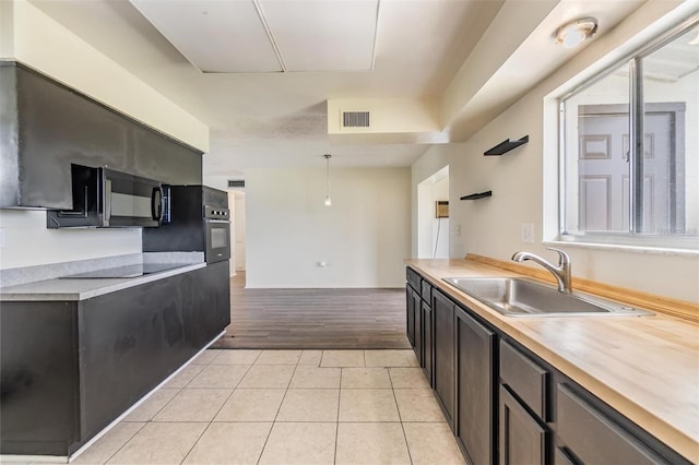 kitchen with visible vents, light tile patterned flooring, a sink, black appliances, and light countertops