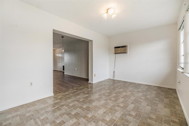 spare room featuring a wall mounted air conditioner and baseboards