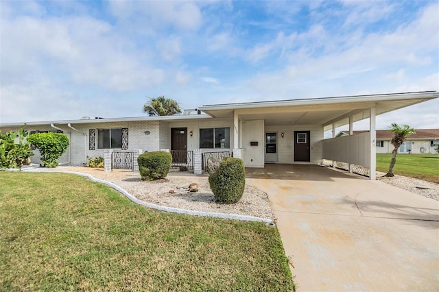 ranch-style home with a carport, covered porch, concrete driveway, a front yard, and brick siding