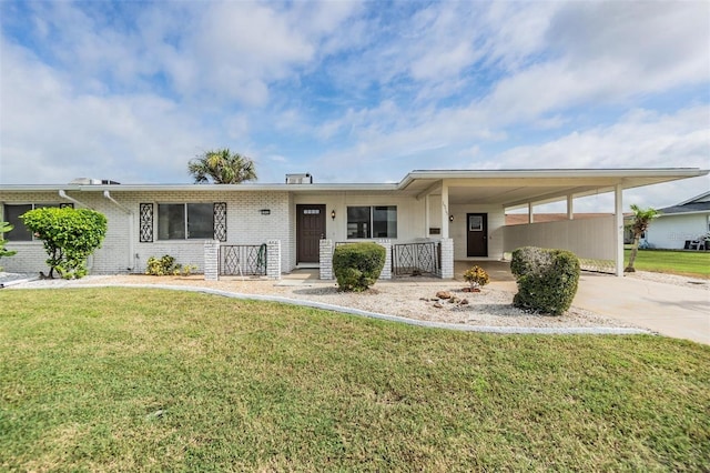 ranch-style home with a carport, concrete driveway, a front lawn, and brick siding