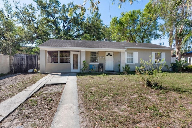 view of front of property featuring stucco siding, a front lawn, and fence