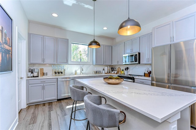 kitchen featuring a sink, light wood-type flooring, tasteful backsplash, and appliances with stainless steel finishes