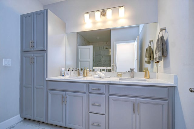 full bathroom featuring baseboards, double vanity, a tile shower, marble finish floor, and a sink