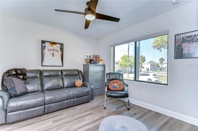 living area with a ceiling fan, baseboards, and wood finished floors