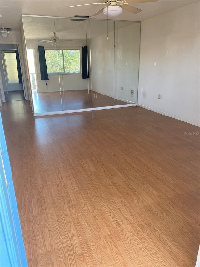 empty room featuring visible vents, ceiling fan, and wood finished floors