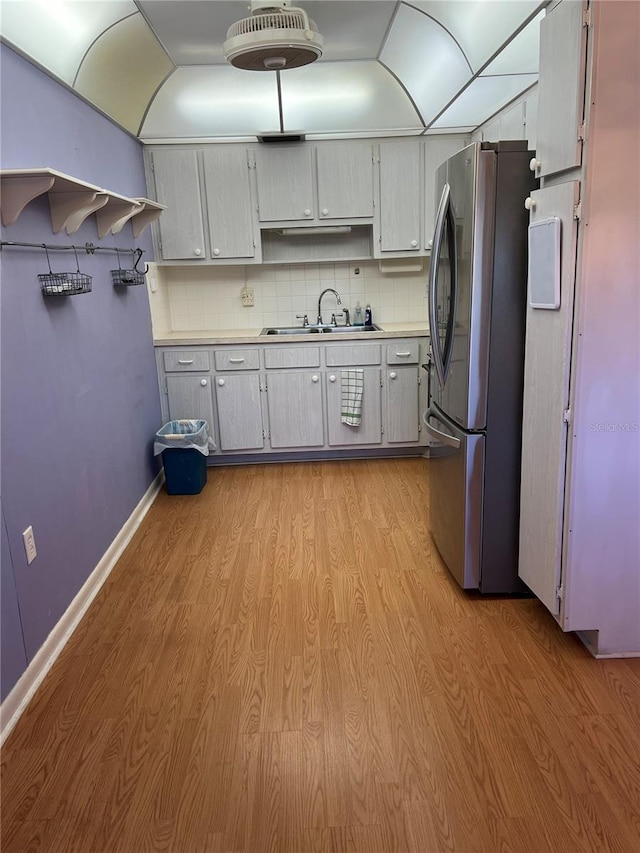 kitchen featuring backsplash, light wood-style flooring, freestanding refrigerator, and a sink