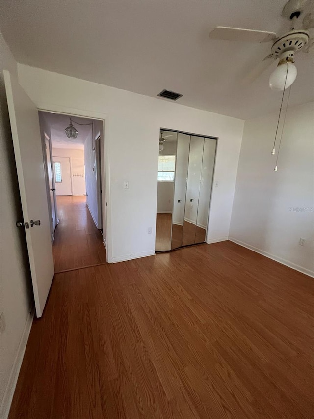 unfurnished bedroom featuring visible vents, baseboards, wood finished floors, and a ceiling fan