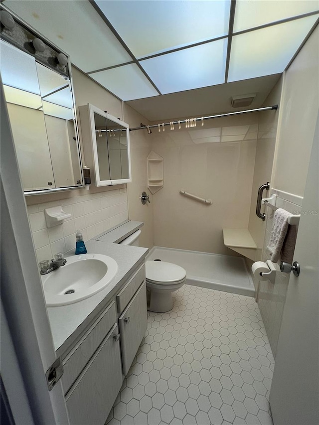 bathroom featuring vanity, decorative backsplash, a shower, tile patterned floors, and toilet