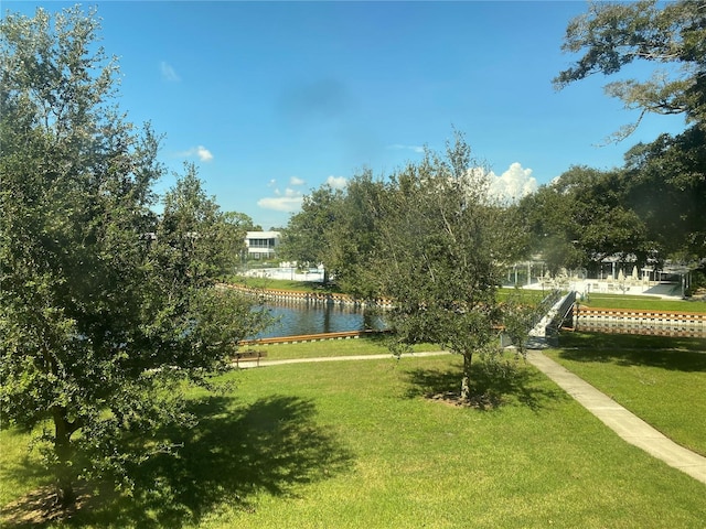 view of property's community with a water view and a lawn