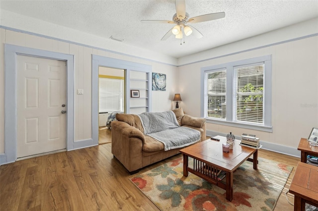 living room with a ceiling fan, wood finished floors, and a textured ceiling