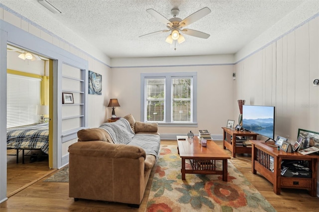 living area with visible vents, a textured ceiling, a ceiling fan, and wood finished floors