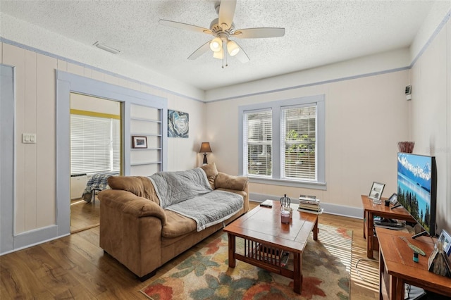 living area with a textured ceiling, wood finished floors, and ceiling fan