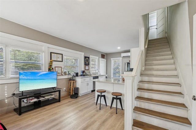 interior space featuring recessed lighting, an AC wall unit, light wood-type flooring, and stairs